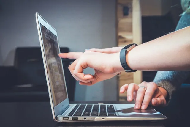 Two people discussing in front of a laptop