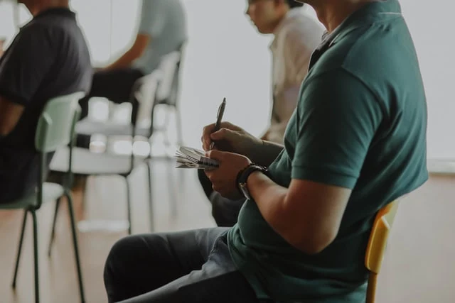 A man on a chair writing notes